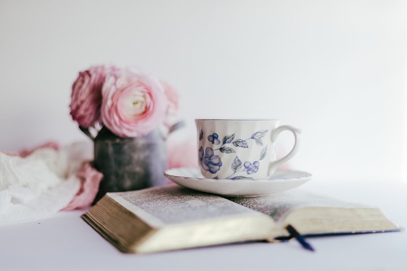 Bible with pink roses and cup of tea